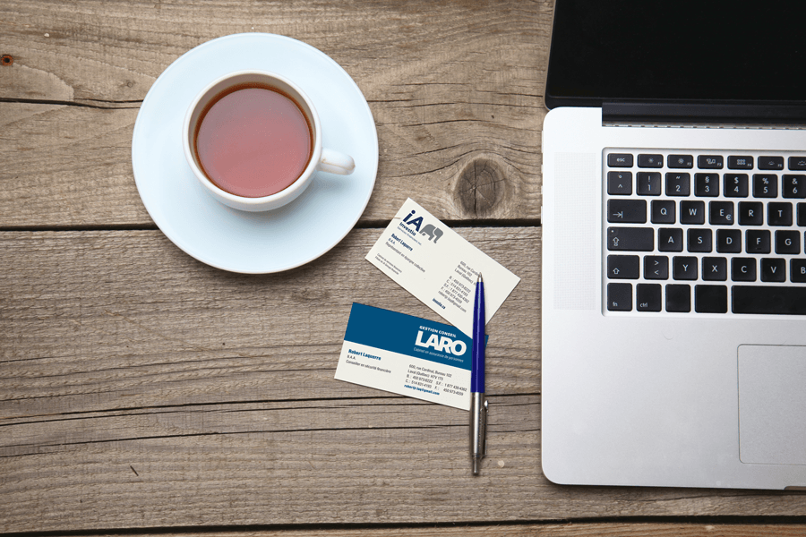 Business cards on table between laptop and cup of tea